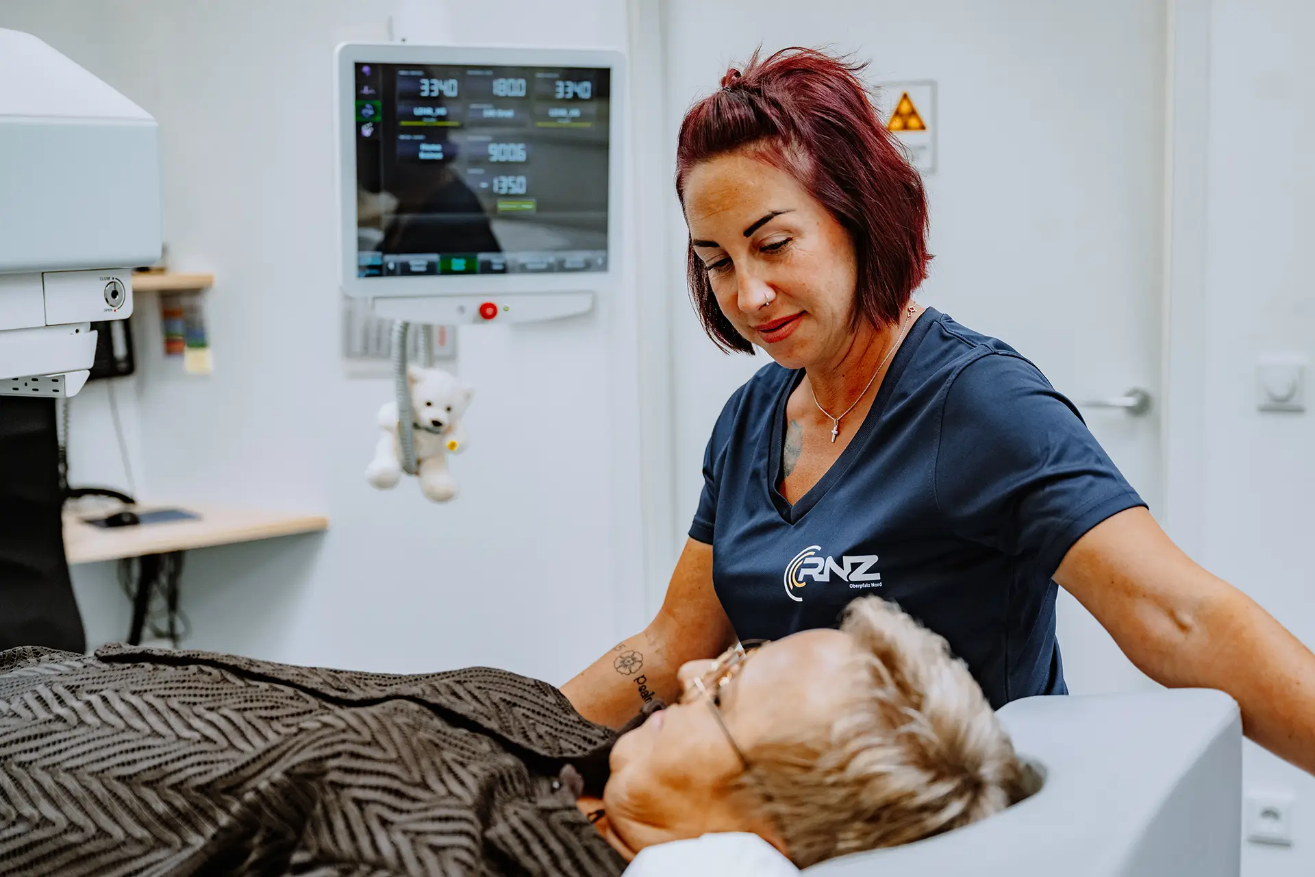 Medizinische Fachangestellte betreut eine liegende Patientin während einer nuklearmedizinischen Untersuchung.