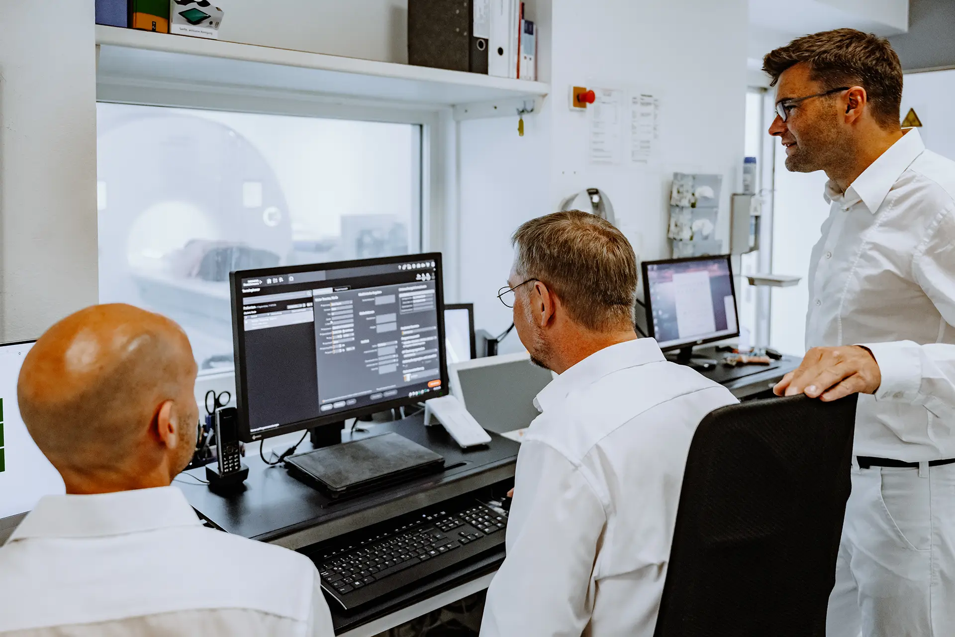 Drei Ärzte des RNZ Oberpfalz Nord besprechen Untersuchungsergebnisse an einem Computerarbeitsplatz.