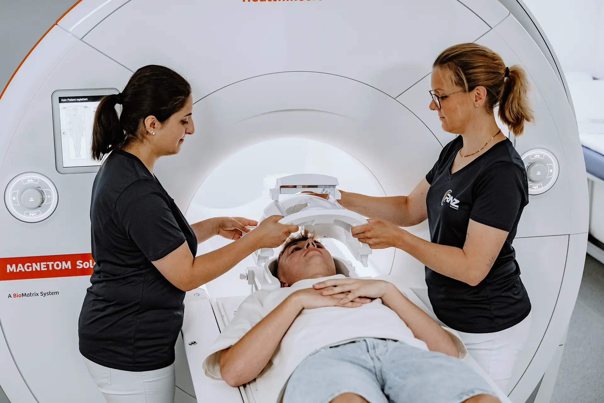 Zwei Mitarbeiterinnen des RNZ positionieren eine Patientin für die MRT-Untersuchung.