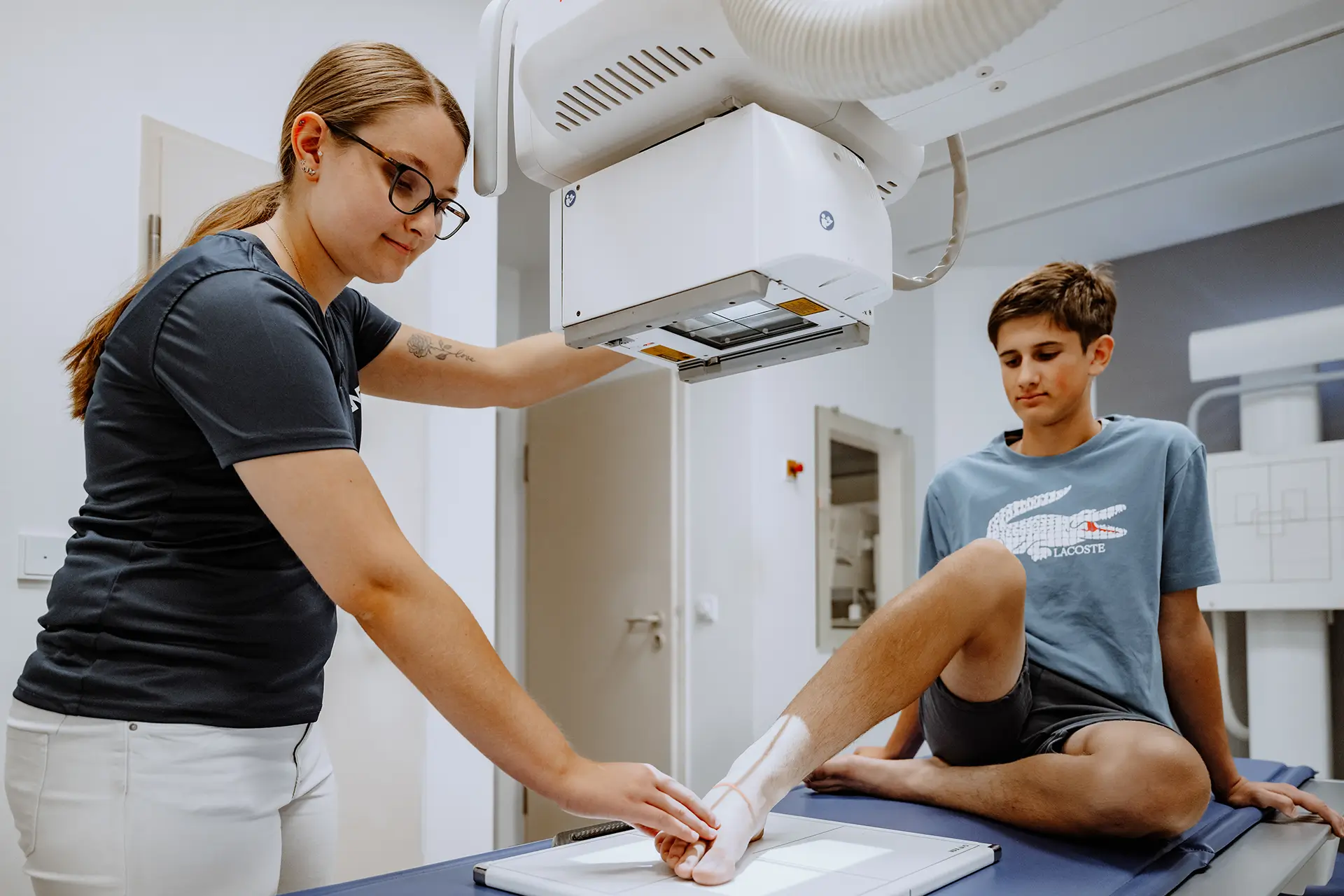 Medizinische Fachangestellte positioniert den Fuß eines jungen Patienten für eine digitale Röntgenaufnahme.